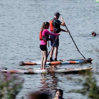 A woman and a man paddleboard together on calm water.